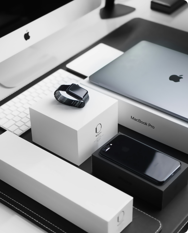 Collection of Apple devices including MacBook Pro, iPhone, Apple Watch and iMac with their packaging boxes.