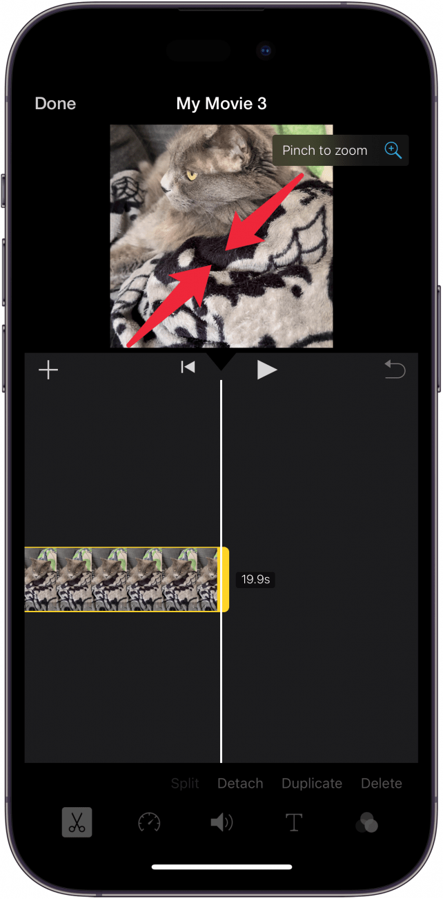 iphone imovie app editing screen with red arrows pointing inward on the the video, indicating for the user to pinch to zoom out on the video